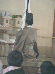 Shinto priest facing offerings.